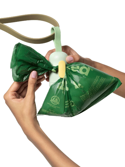 Person using a green pet waste bag with a white handle on a white background