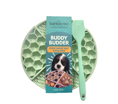 Green enrichment mat with a spatula and packaging labeled 'Buddy Budder' on a white background.