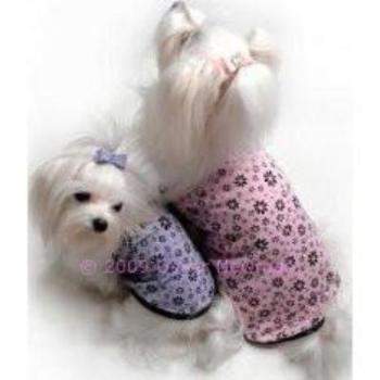 Two small white dogs, wearing Oscar Newmans Moonlit Dog Tees with a sparkling flower print, sit facing each other. One wears pink with a bow; the other shines in blue. Their outfits perfectly capture the playful elegance of the stretch polyester/lycra material.