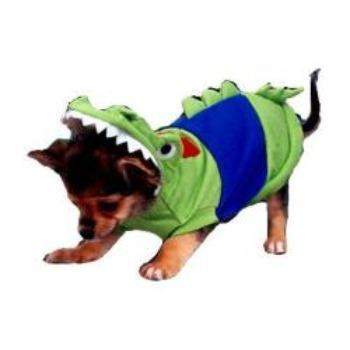A small dog struts in its vibrant green Crocodile Costume by Pampet/Puppe Love, featuring a toothy hood and blue back detailing. This adorable pet bodysuit adds a playful touch to any outing as the dog walks confidently, casting curious glances downward.