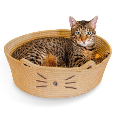 A cat rests comfortably in a tan round basket, designed as a convertible cat bed and toy storage bin.