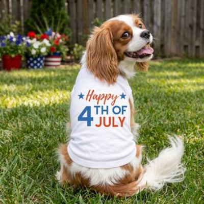 Dog sitting on grass wearing white Happy 4th of July shirt 