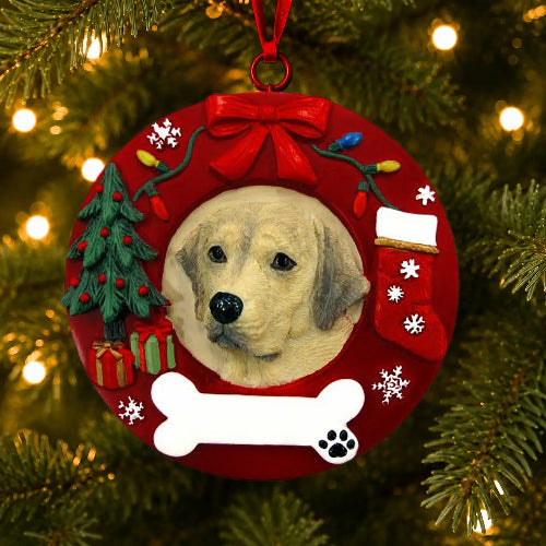 A round red Christmas ornament hanging on a lit Christmas tree. The ornament features a portrait of a Yellow Labrador Retriever in the center, surrounded by a red holiday wreath design with a red bow, colorful lights, a small Christmas tree, a stocking, snowflakes, a white bone, and a black paw print detail.