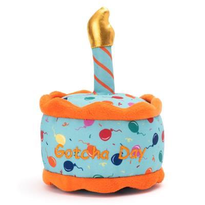A plush dog toy designed to look like a birthday cake with 'Gotcha Day' text on it, featuring colorful decorations and a golden candle.