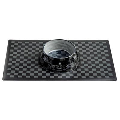 Black and silver cylindrical object on a checkered mat with 'Chewy Vuiton' branding.