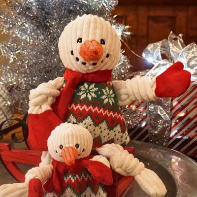 Decorative snowman dog toy with a smaller snowman toy in a sleigh, surrounded by festive decorations.
