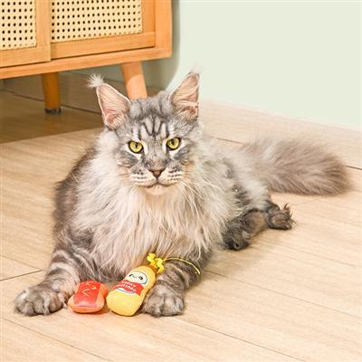 Gray cat lying on a wooden floor with two toys in front of it.