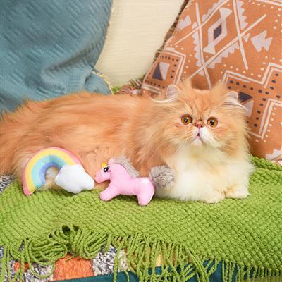 Cat sitting on a green blanket with colorful plush toys