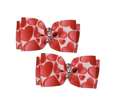 Two red and white heart-patterned hair bows with silver centers on a white background.