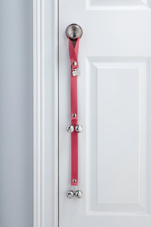 French Rose Pink PoochieBells Premium Full Grain Leather Dog Doorbells hanging on doorknob on white door.