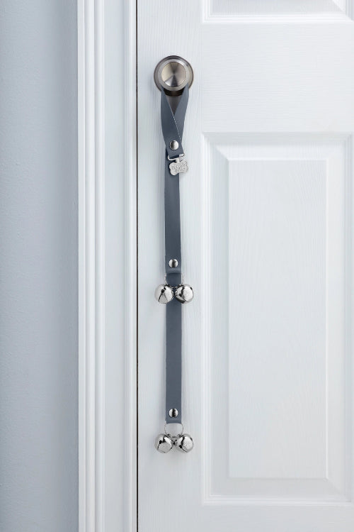 Rolling Fog Gray PoochieBells Premium Full Grain Leather Dog Doorbells hanging on doorknob of white door.