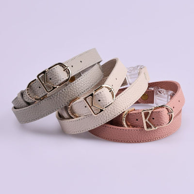 Three dog harnesses with gold buckles on a light purple background