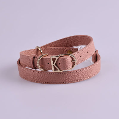 Pink dog harness with gold buckle on a light purple background