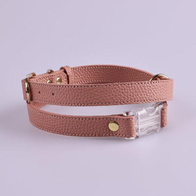 Pink leather dog harness with a clear plastic buckle on a light purple background