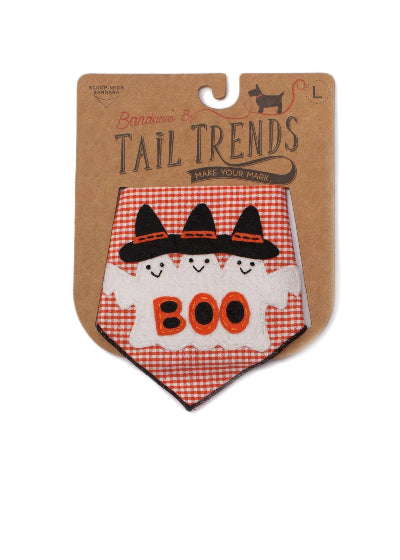 A Halloween-themed dog bandana by Tail Trends, displayed on its brown cardboard backing. The bandana features a orange and white gingham pattern with three embroidered black witch hats and a white ghost body containing the word 'BOO' in orange.