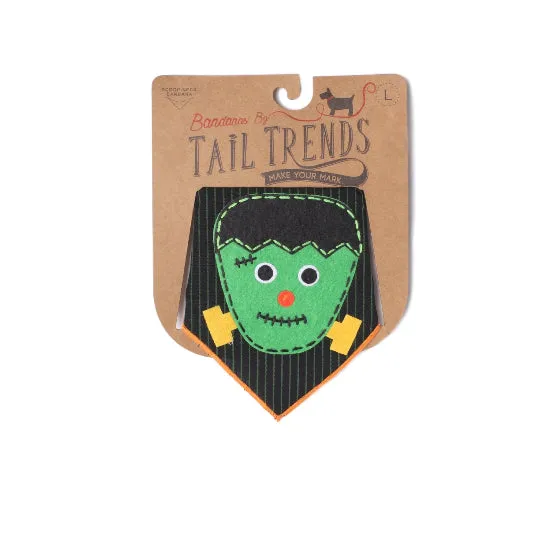 A Halloween-themed cotton bandana in Frankenstein's monster style, displayed on its original kraft paper packaging card. The bandana features green felt hair, a black pinstripe body, yellow hands, and a red nose.