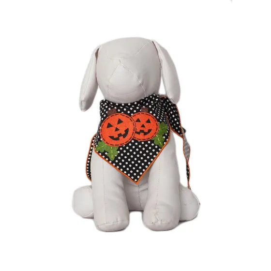 A white plush stuffed dog wearing a black and white polka dot bandana with two orange pumpkin patches and green leaves, shown against a plain white background.