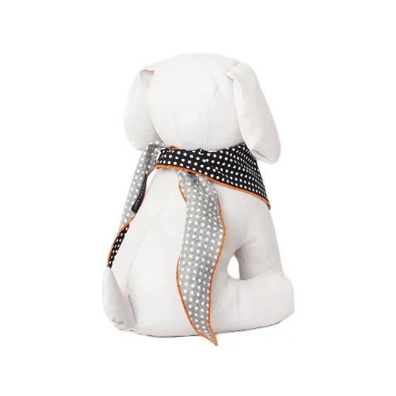 A white plush stuffed dog toy shown from the back, wearing a black and white polka dot scarf with orange trim.