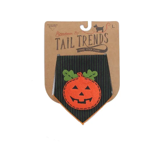 A Halloween-themed dog bandana by Tail Trends, shown in its cardboard packaging. The bandana is black with thin green pinstripes, featuring a large orange pumpkin applique with green leaves and a stitched jack-o'-lantern face.