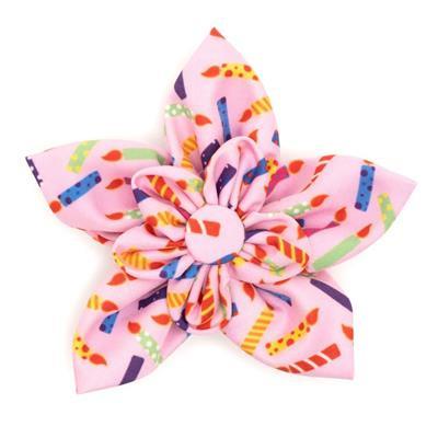 Colorful pink flower-shaped hair bow with birthday themed pattern on a white background