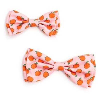Two pink dog bow ties with patterns of peaches on white background
