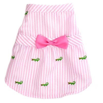 Pink and white striped dress with a large pink bow and small green alligator patterns on a white background