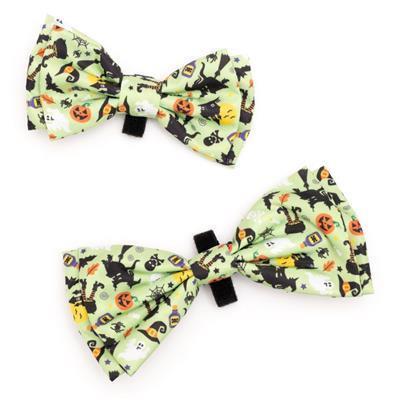 Two Halloween-themed bow ties with black cats, pumpkins, and ghosts on a light green background.