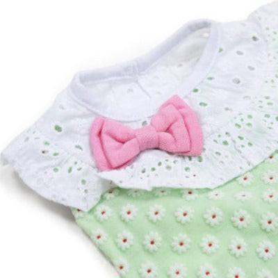 Baby outfit with white collar and pink bow on a green floral background