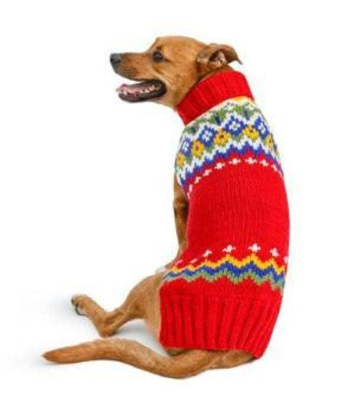 Dog wearing a red hand-knit wool Fairisle sweater with colorful geometric patterns and a cozy turtleneck collar on white background